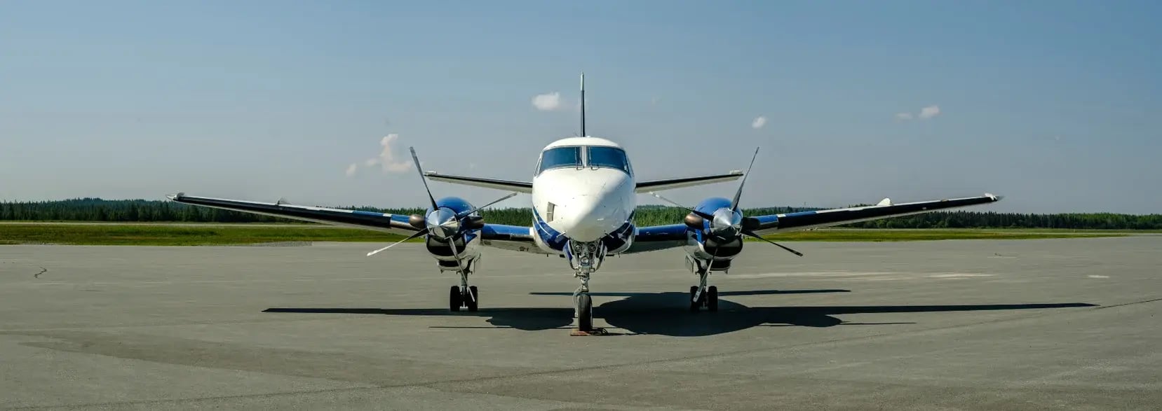 Un avion King Air A100 stationné sur le tarmac par une journée d’été.