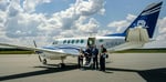 Deux infirmiers, accompagnés de deux pilotes, posent devant un avion-ambulance de Propair avec du matériel de réanimation.