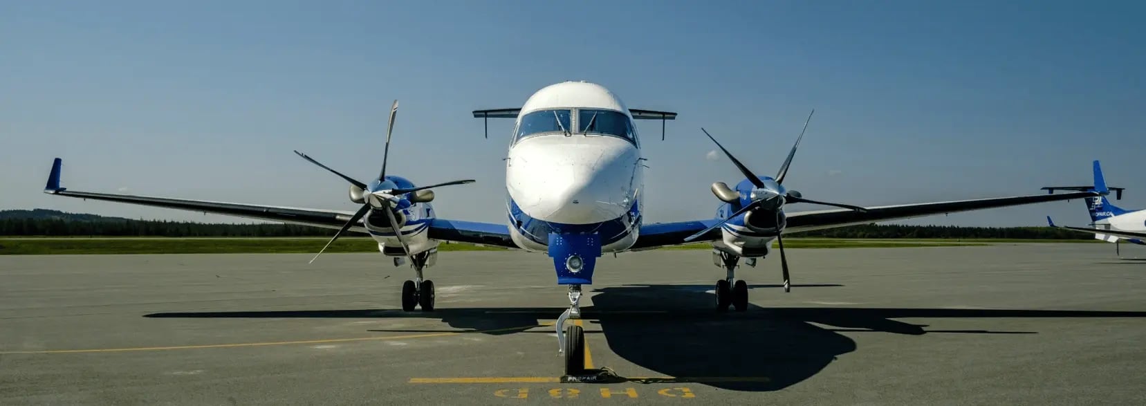 Un avion B1900D stationné de face sur le tarmac par une journée d’été.