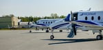Deux avions B1900D sont stationnés parallèlement sur le tarmac par une journée d’été.