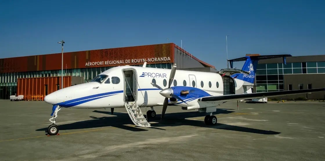 Un avion B1900D est stationné sur le tarmac devant l'aéroport de Rouyn-Noranda par une journée d’été.