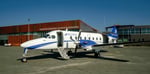 Un avion B1900D est stationné sur le tarmac devant l'aéroport de Rouyn-Noranda par une journée d’été.