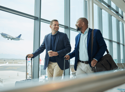 Two businessmen are traveling through an airport.