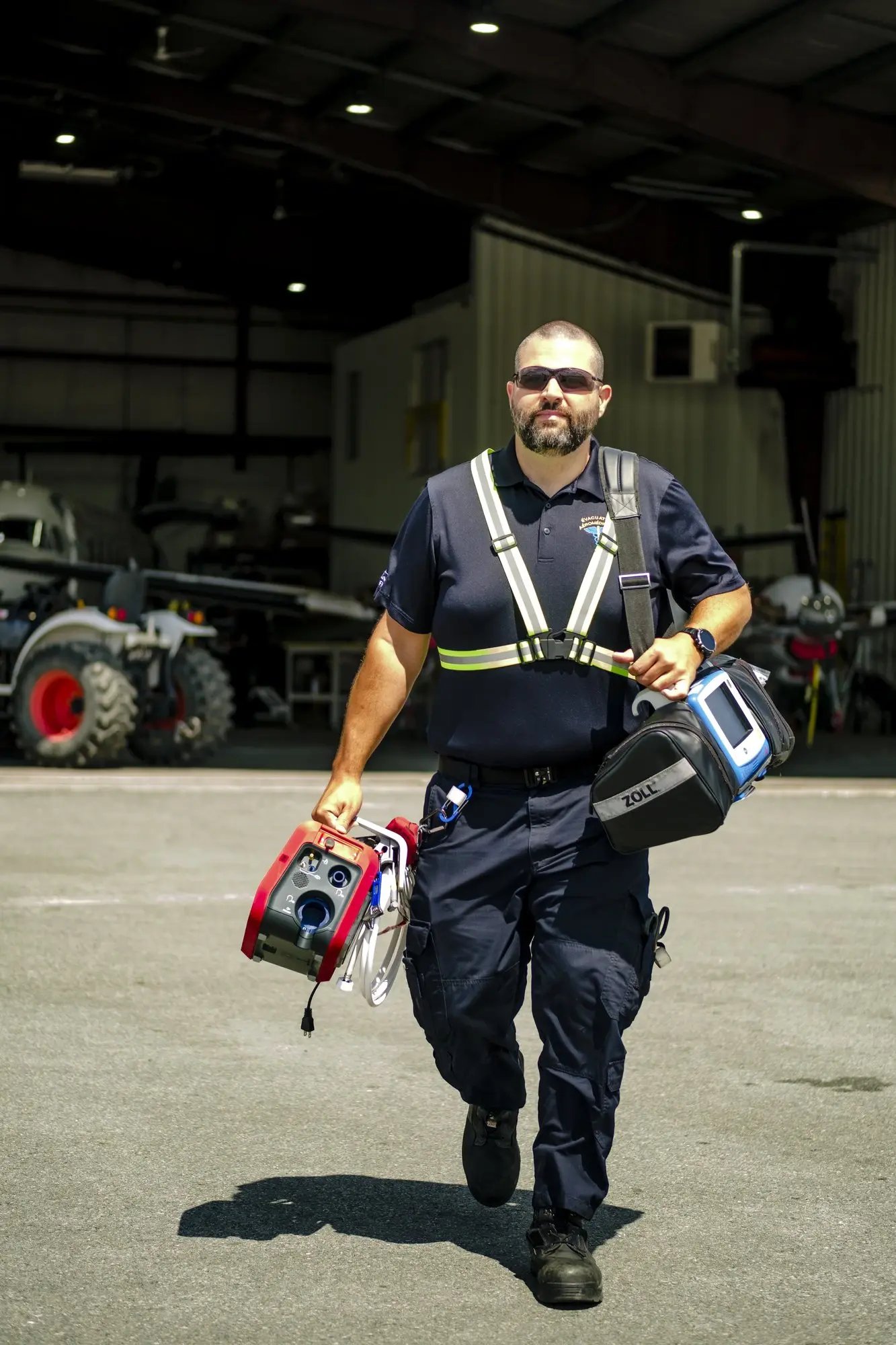 Un infirmier de vol marche sur le tarmac avec un réanimateur cardiaque dans les mains. 